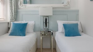 A hotel room with two beds, a nightstand with a lamp, a mirror, and a window with curtains. - Le Chambre d’Isabel - Close to shops, bars and places to eat & the beach (Dorset)