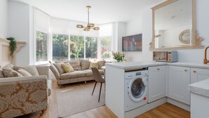 A modern kitchen with a built-in washer, a large mirror, and a dining area with a sofa. - Le Chambre d’Isabel - Close to shops, bars and places to eat & the beach (Dorset)