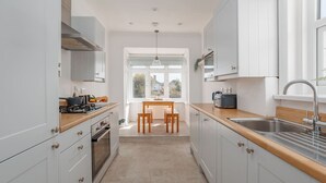 A modern kitchen with white cabinets, a wooden countertop, a built-in oven, and a window providing natural light. - Beaufort Heights - Well located for Christchurch and the beaches (Dorset)