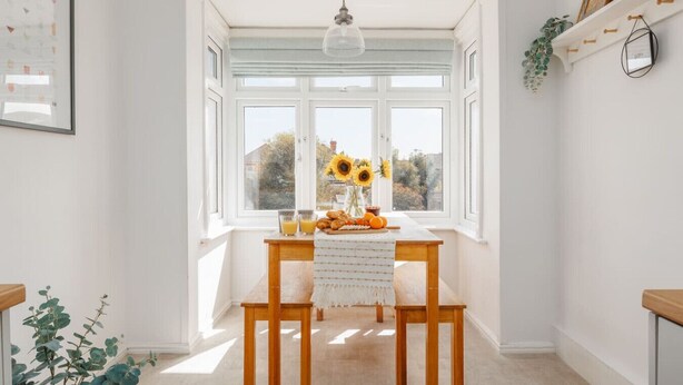 A bright room with a large window, a wooden table with a white cloth, and a hanging light fixture. - Beaufort Heights - Well located for Christchurch and the beaches (Dorset)