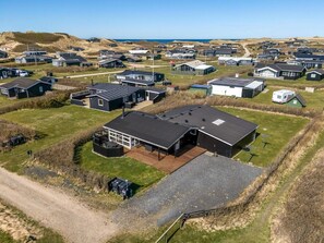 An aerial view of a residential area with houses, a large building with a garage, and a dirt road. - 4 Star Holiday Home in Lokken (Lokken)
