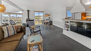 A modern interior with a dining area, kitchen, and seating space. - 4 Star Holiday Home in Lokken (Lokken)