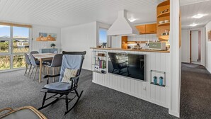 A modern interior with a dining area, a TV, and a kitchen with wooden cabinets. - 4 Star Holiday Home in Lokken (Lokken)