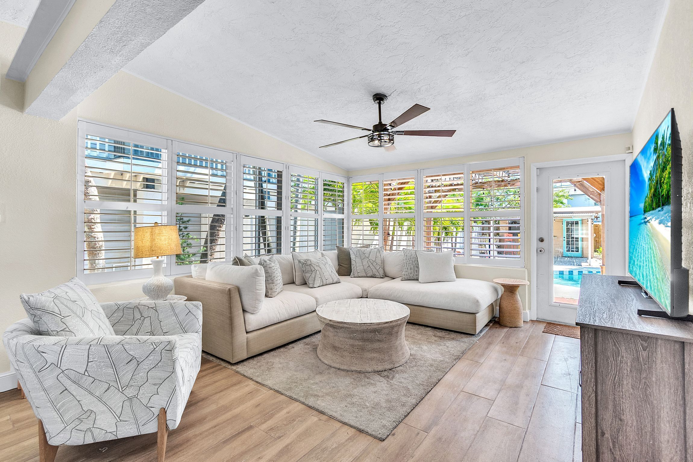 A modern living room with a sectional sofa, a round coffee table, and a ceiling fan.