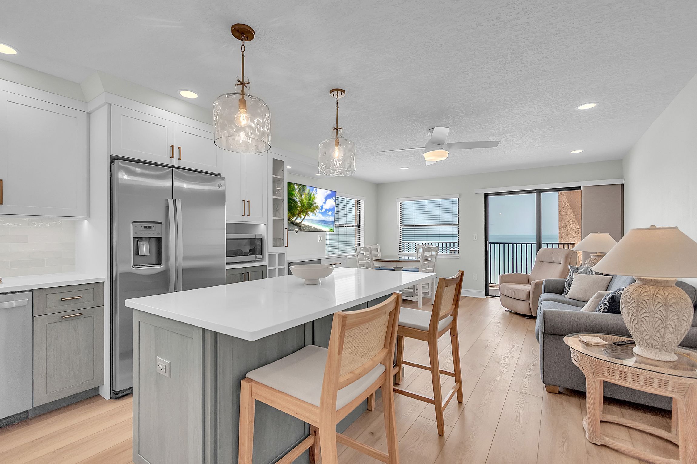 A modern kitchen with a large island, stainless steel appliances, and pendant lighting.
