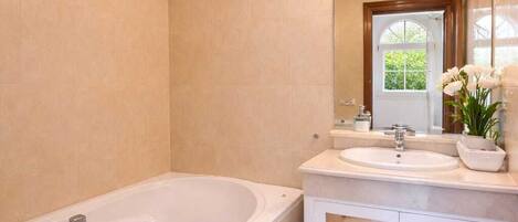 A bathroom with a bathtub, toilet, and vanity with a mirror and sink.