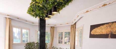 Un salón de conferencias con una larga mesa, sillas negras, individuales tejidas y una planta verde colgante.