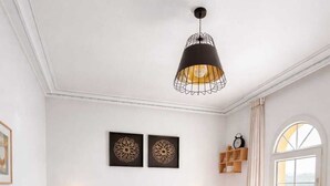 Ett sovrum med en säng, sänglampor, en rund, vävd matta, en stol och en hängande lampa.
