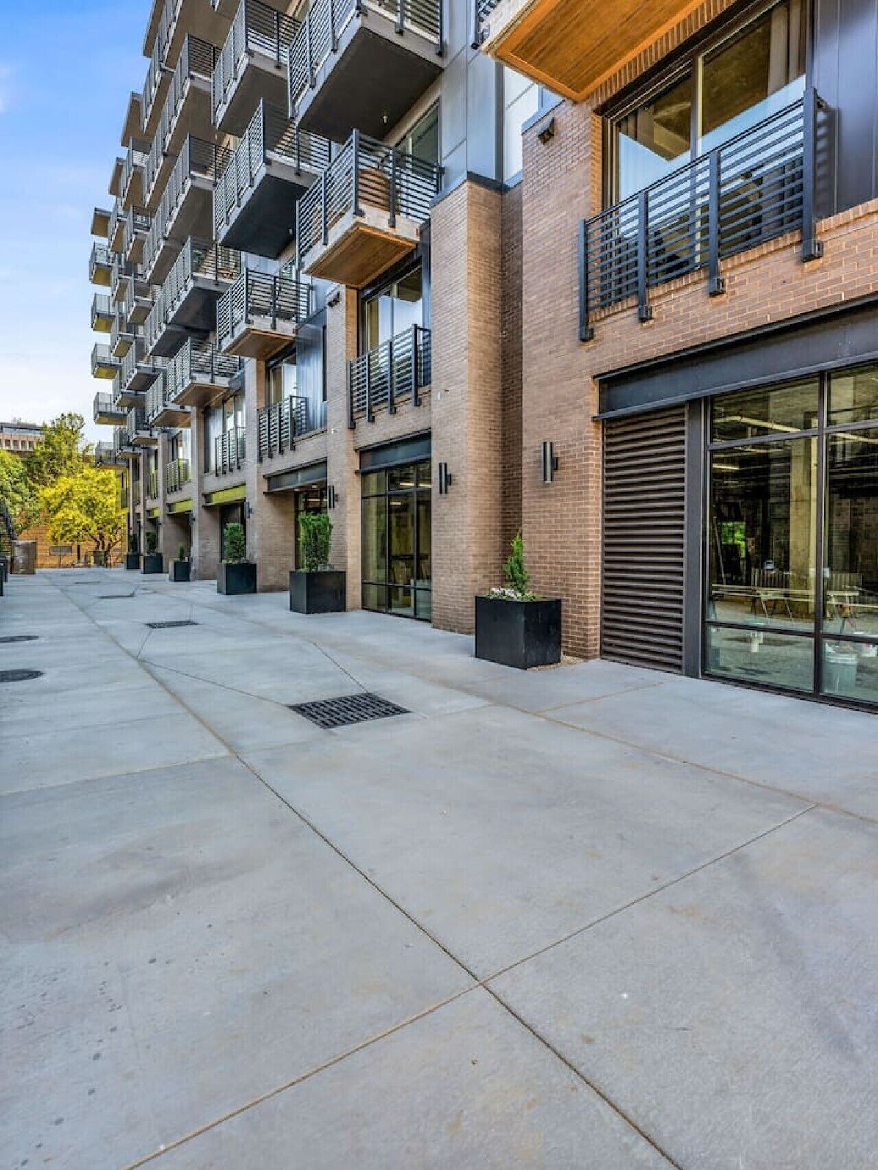 A multi-story residential building with balconies, large windows, and a paved courtyard.