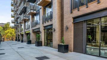 A multi-story residential building with balconies, large windows, and a paved courtyard.