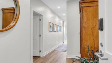 A hallway with wooden flooring, white walls, and a wooden door with a modern handle.