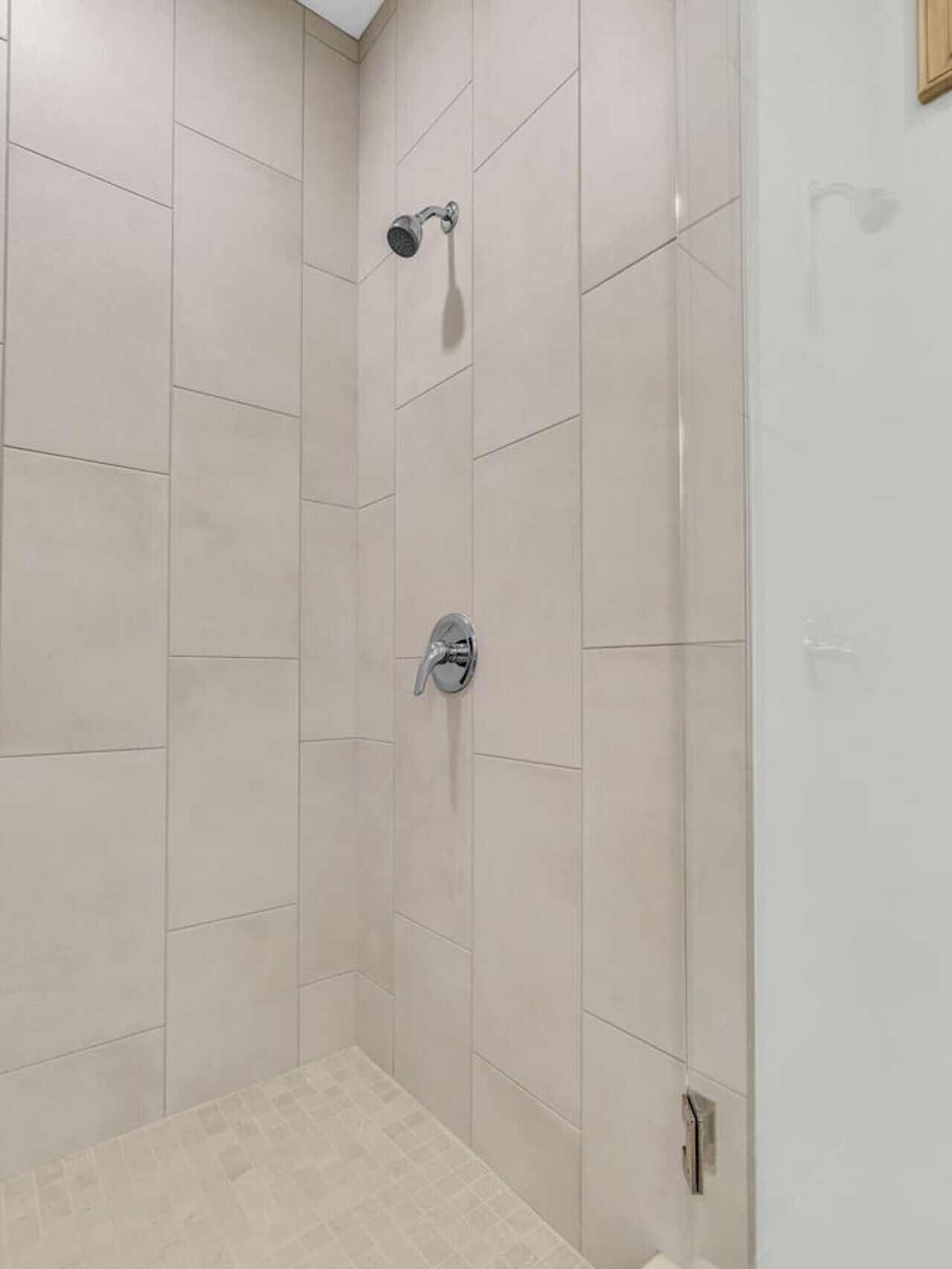 A shower area with tiled walls and floor, a showerhead, and a faucet.