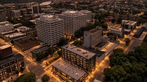 An urban cityscape at dusk with high-rise buildings, a parking lot, and a river in the background. - Lone Tree Pass | King + Queen | Balcony + Parking (Knoxville)