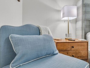 A bed with a headboard, a bedside table with a lamp, and a nightstand with books and a remote control. - Lone Tree Pass | King + Queen | Balcony + Parking (Knoxville)