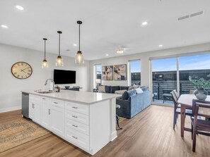 Une cuisine moderne dotée d’un îlot central, de luminaires suspendus et d’un coin repas avec une table et des chaises.