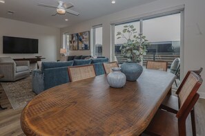 A modern living room with a dining table, sofas, a TV, and a large window. - Lone Tree Pass | King + Queen | Balcony + Parking (Knoxville)