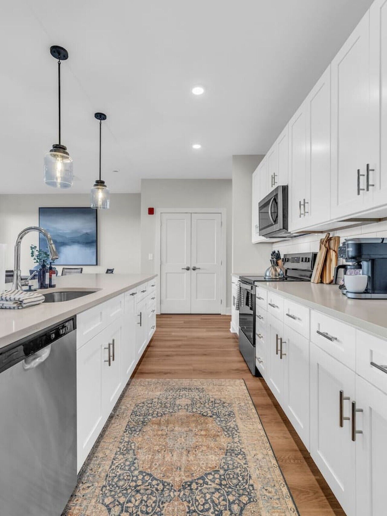 A modern kitchen with white cabinetry, a central island, a microwave, and a coffee maker.