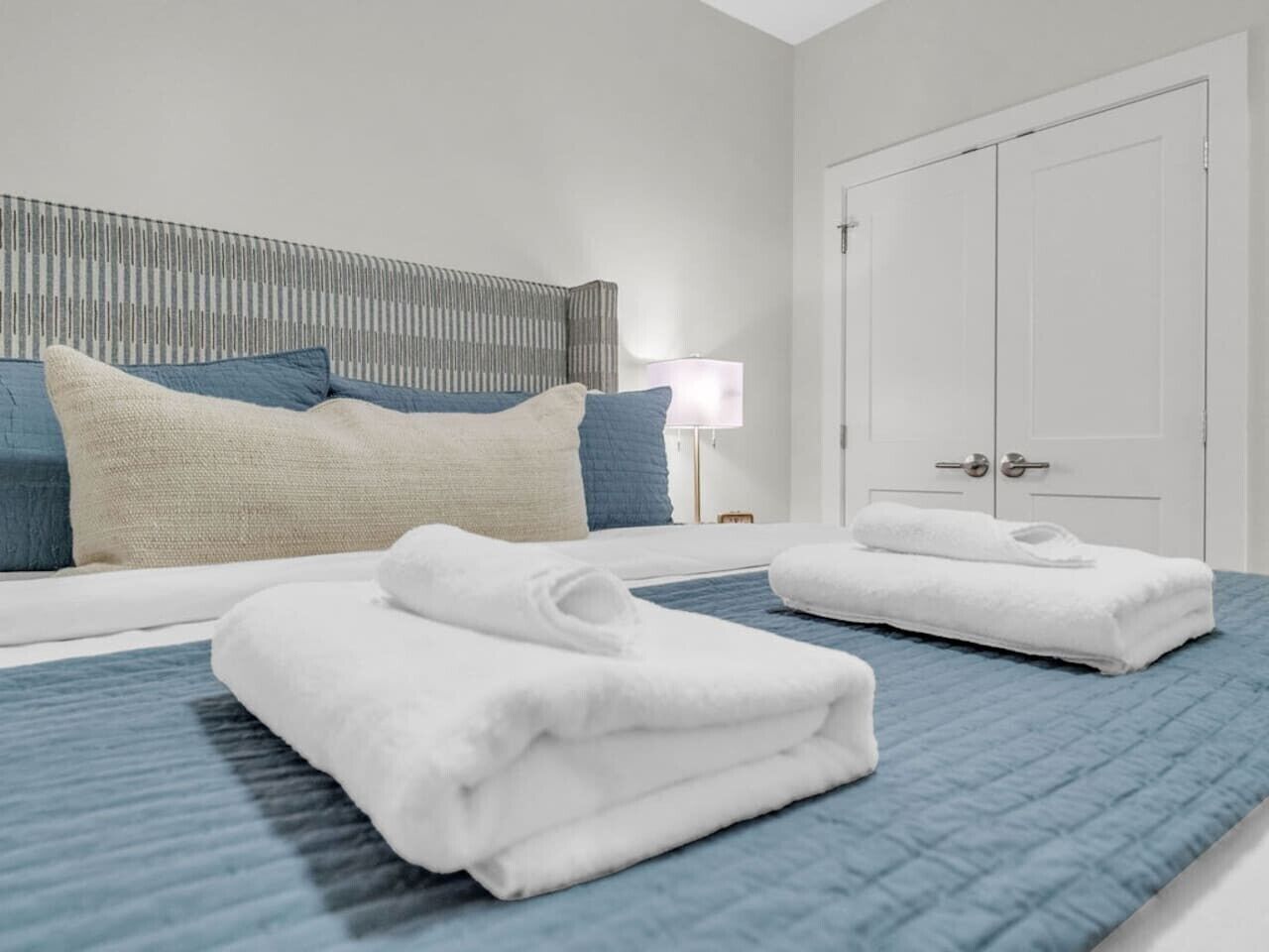 A hotel room with a bed, a nightstand, a lamp, and a wardrobe.