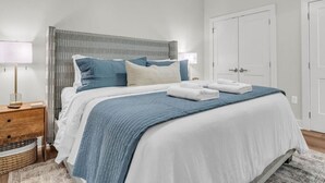 A bedroom with a bed, bedside tables, a lamp, and a door. - Lone Tree Pass | King + Queen | Balcony + Parking (Knoxville)
