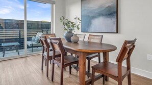 A dining area with a round table, six wooden chairs, a vase, and a large abstract painting on the wall. - Lone Tree Pass | King + Queen | Balcony + Parking (Knoxville)