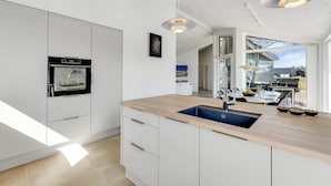 Een moderne keuken met een ingebouwde oven, een spoelbak en een eethoek met uitzicht.