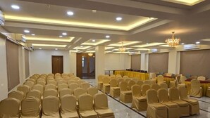 Ein Konferenzraum mit Reihen von Stühlen, einem roten Teppich und einer Kristallleuchtre.