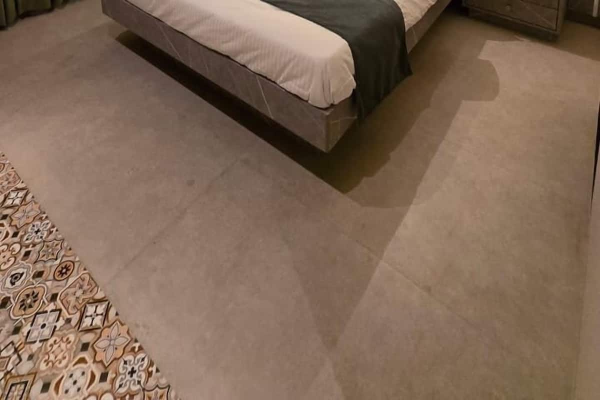 Ein modernes Hotelzimmer mit einem großen Bett, zwei Nachttischen, einem Deckenventilator und einem gemusterten Teppich.