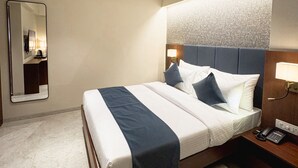 Ein Hotelzimmer mit Bett, Deckenventilator, Nachttisch mit Lampe und Spiegel.