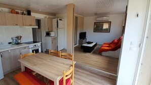 Eine kleine Küche mit Essbereich, einer Mikrowelle, einem Kühlschrank und einem Fernseher.