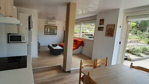 Eine moderne Küche mit Mikrowelle, ein Essbereich mit Tisch und Stühlen sowie ein Blick ins Freie durch ein Fenster.