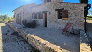 A stone building with a patio, outdoor seating, and a view of the countryside. - Le Puits des Oliviers (Puimoisson)
