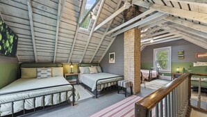 A loft bedroom with a sloped ceiling, two beds, a brick column, and a view of the outdoors. - The Nordic cottage, huge modern pool, hot tub. (Union Pier)