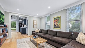 A spacious living room with a large brown sofa, a wooden coffee table, and a kitchen in the background. - The Nordic cottage, huge modern pool, hot tub. (Union Pier)