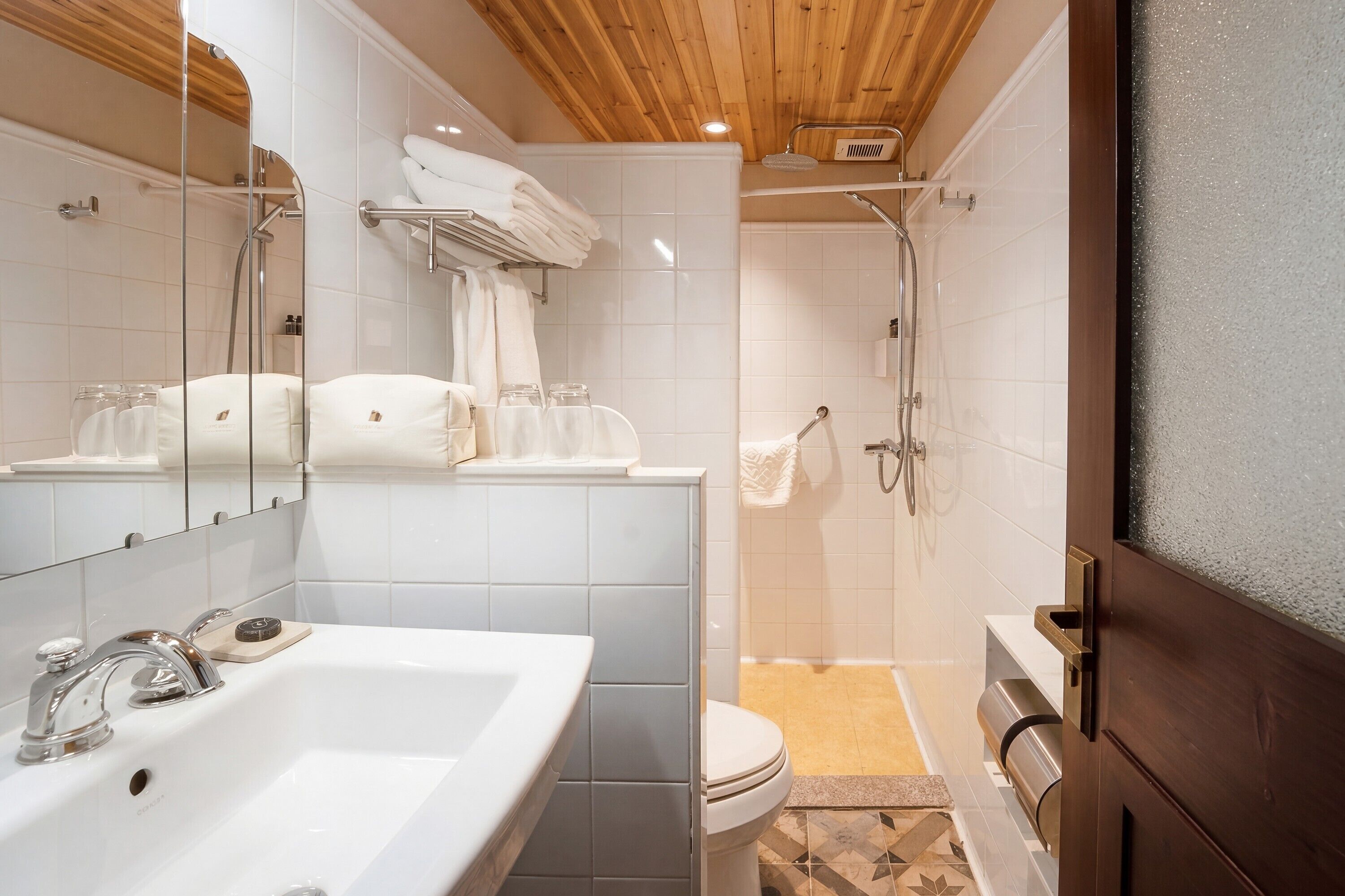 A modern bathroom with a white sink, mirror, and shower.