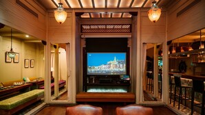 Een gezellige woonkamer met een televisie, houten meubels en een barretje.