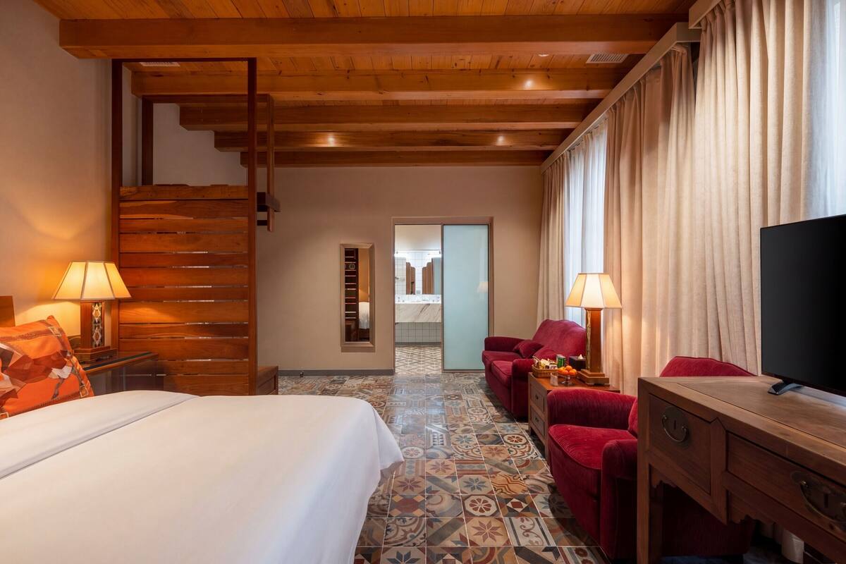 Una habitación de hotel con cama, televisión, escritorio, silla y escalera.