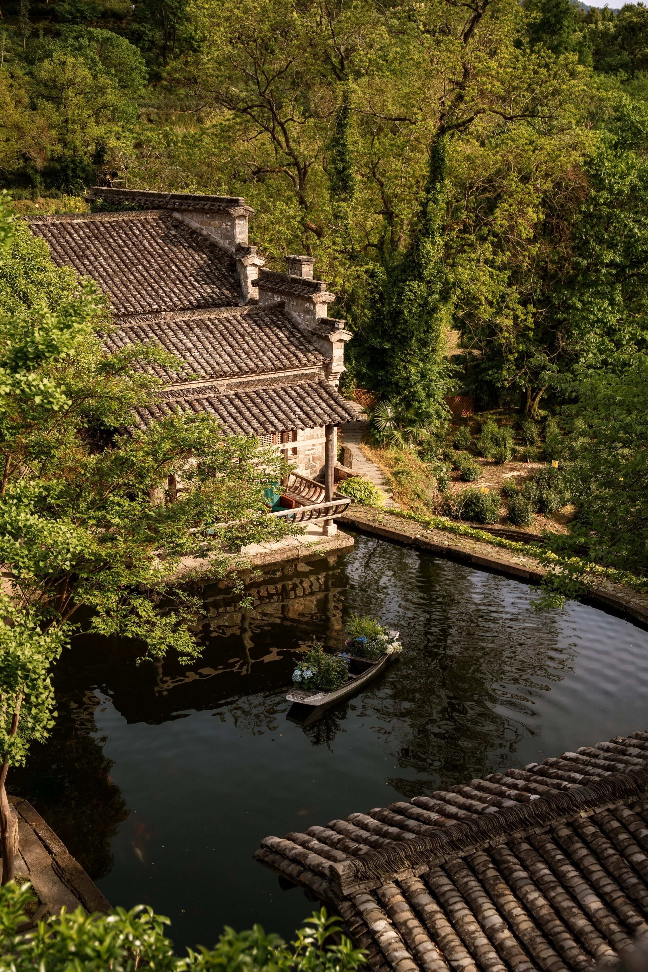 A traditional building with a tiled roof, a stone pathway, and a calm water body.