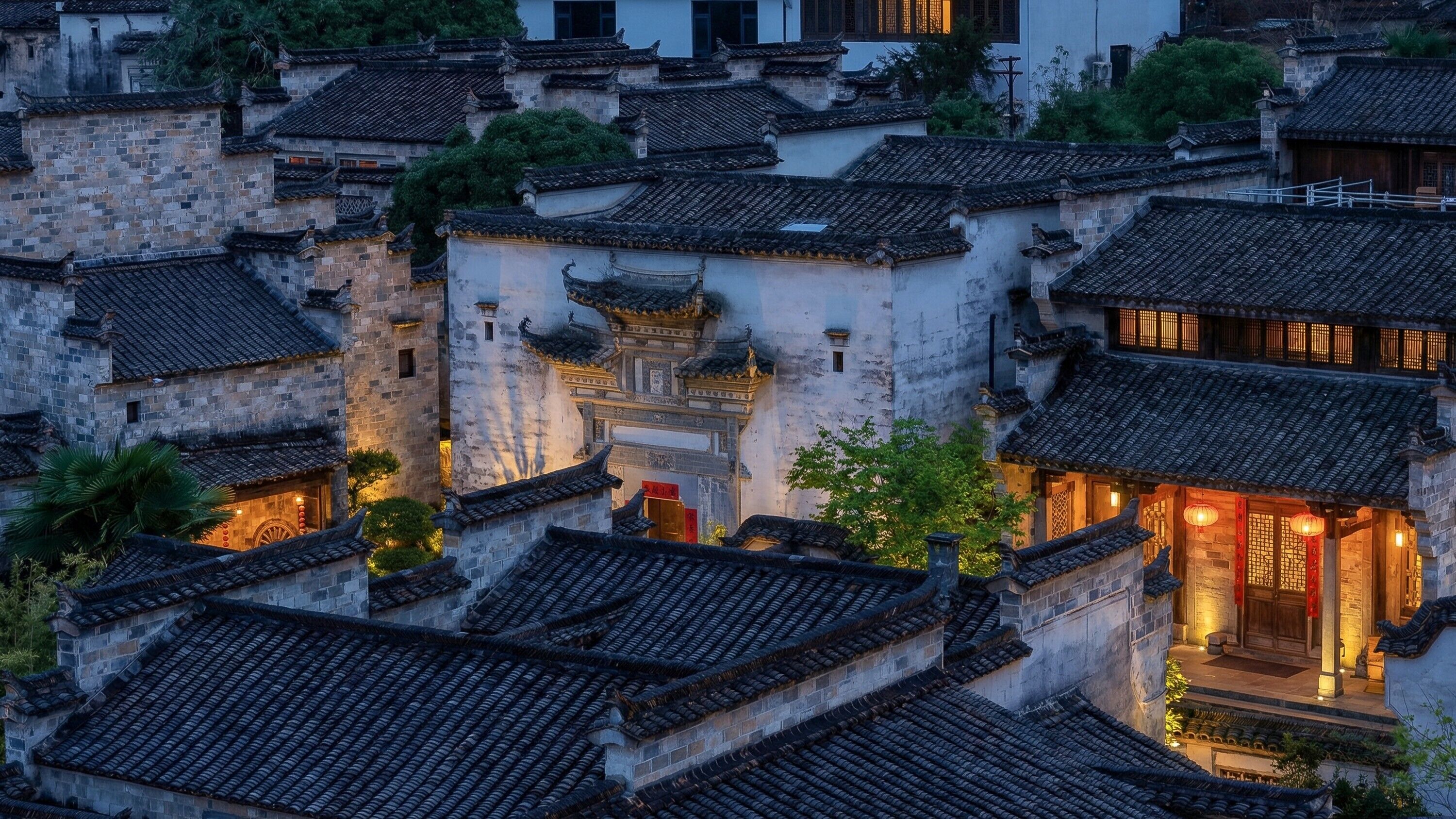 A traditional Chinese courtyard with stone buildings, tiled roofs, and a central gate.