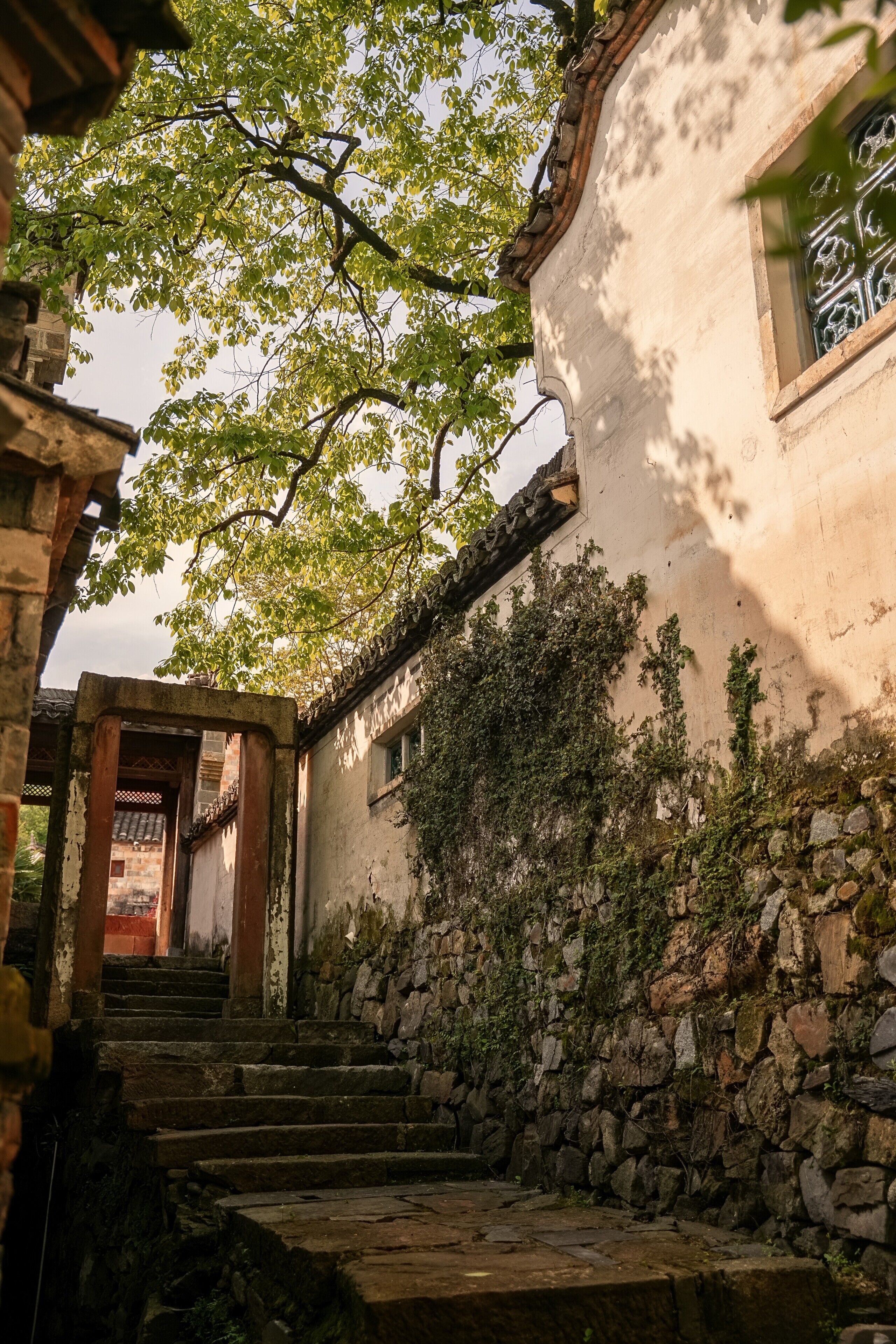 A stone staircase leading to a building with a traditional tiled roof and a window with decorative patterns.