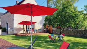 A patio with red chairs and umbrellas, a stone wall, and a grassy lawn. - Le colibri - Country house with private pool (Chambourg-sur-Indre)