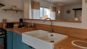 A kitchen with a sink, a toaster, a kettle, and a window with curtains. - Le colibri - Country house with private pool (Chambourg-sur-Indre)