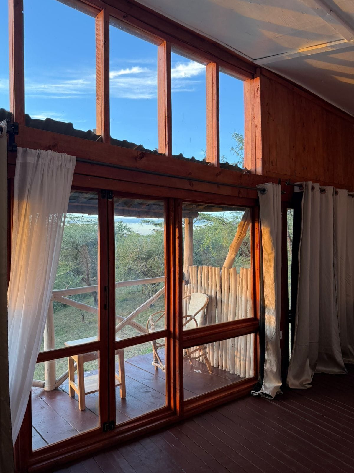 Una habitación con ventanas amplias, vigas de madera y vistas al exterior.