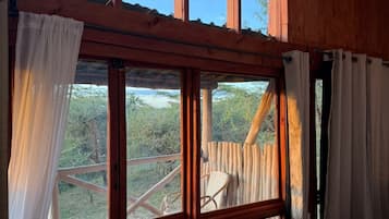 Una habitación con ventanas amplias, vigas de madera y vistas al exterior.
