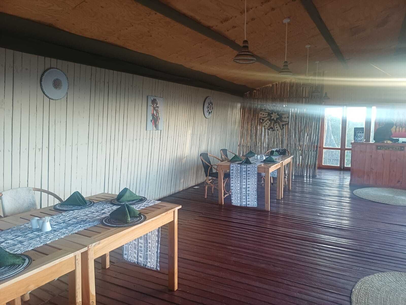 Una habitación con pisos de madera, una mesa de comedor con individuales verdes y una pared con listones de madera verticales.