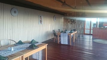 Una habitación con pisos de madera, una mesa de comedor con individuales verdes y una pared con listones de madera verticales.
