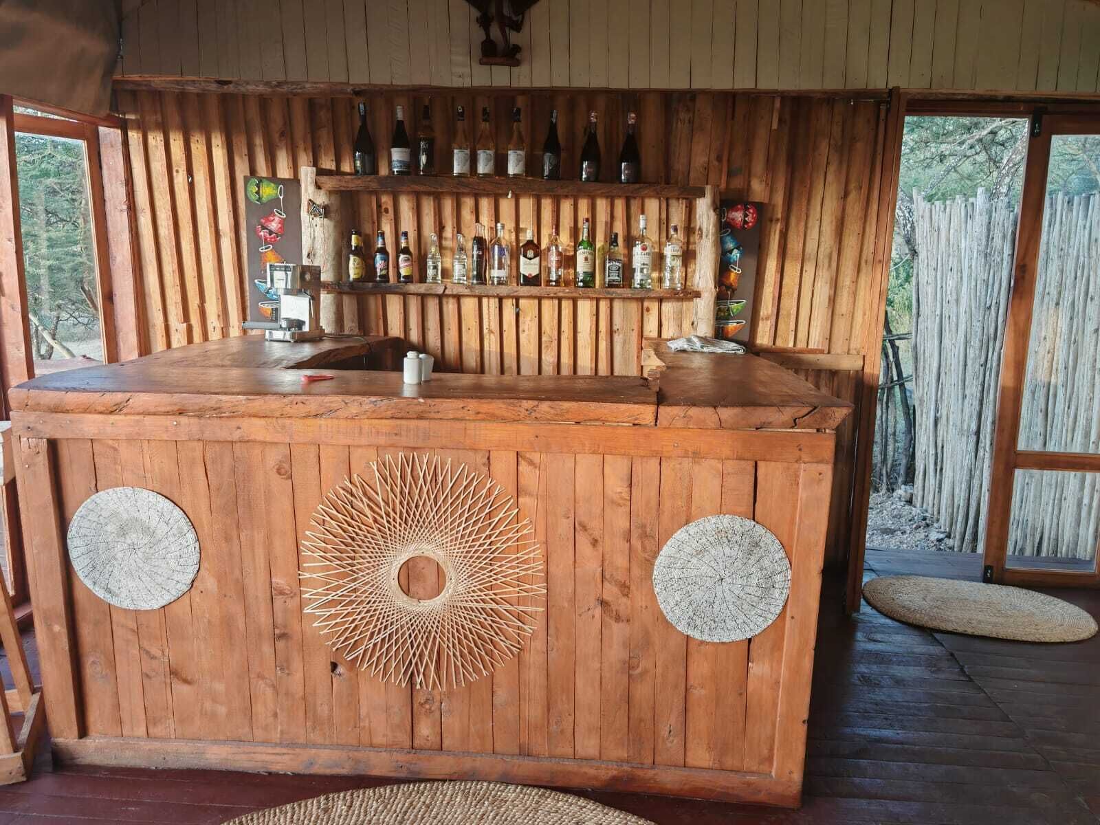Una barra de madera con un diseño circular, botellas y ambiente rústico.