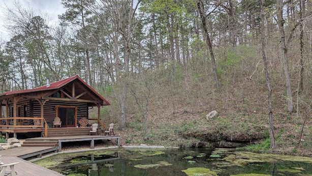 A log cabin with a deck and a pond with lily pads. - Luxury Craftsman 1-bedroom cabin in SERENE beauty with AC, high end kitchen/bath (Ava)