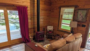 A cozy cabin interior with a wooden interior, a sofa, a table, and a fireplace. - Luxury Craftsman 1-bedroom cabin in SERENE beauty with AC, high end kitchen/bath (Ava)