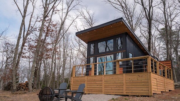 Een chalet met terras, twee stoelen, een tafel en een vuurkuil.
