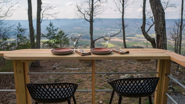 Ein Holztisch mit zwei Stühlen für zwei Personen, mit Blick auf eine schöne Landschaft.